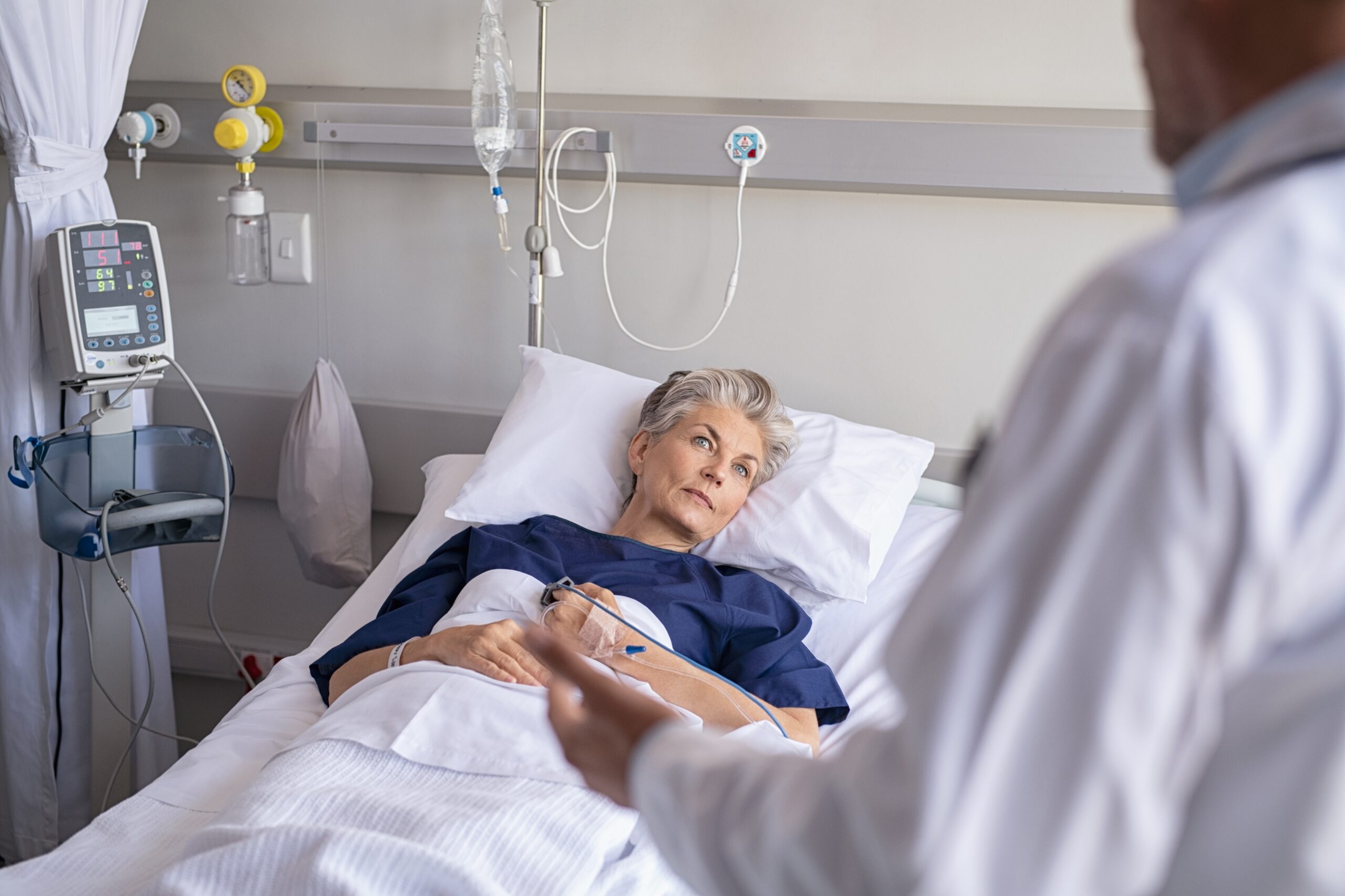 Senior,Woman,Lying,On,Hospital,Bed,And,Listening,To,Doctor